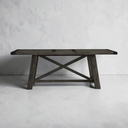 Wooden table with X-shaped legs against a gray concrete wall.