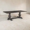 Wooden dining table with a rustic design on a plain floor.