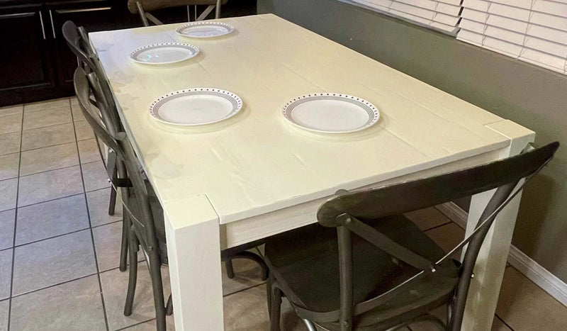 Dining table with four plates and four chairs in a kitchen setting